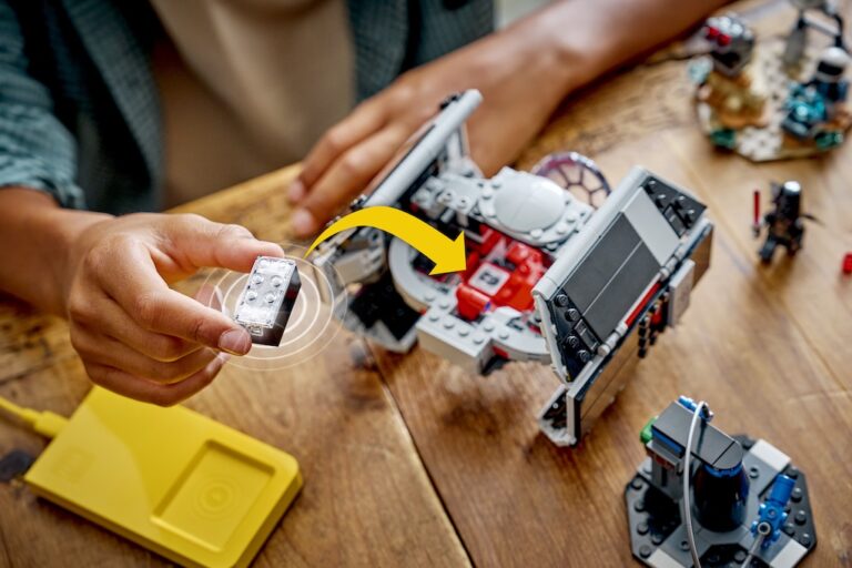 Hand hält einen LEGO SMART Brick und setzt ihn in ein Star-Wars-TIE-Fighter-Modell ein