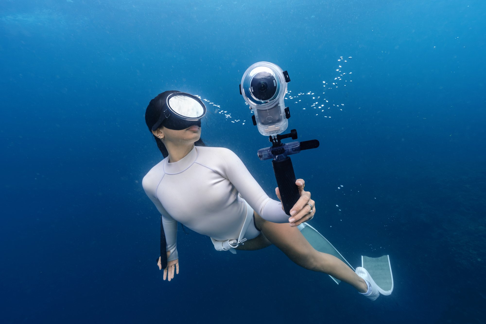 Weiße Insta360 X6 beim Tauchen Taucherin hält die schwarze Insta360 X6 am Selfie-Stick unter Wasser