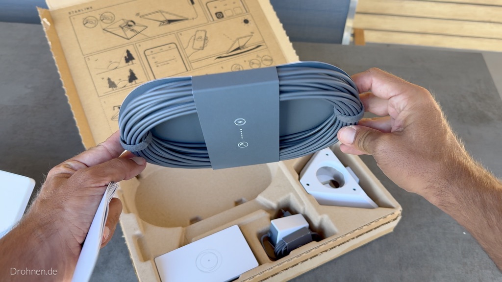 Aufgerolltes graues DC-Stromkabel des Starlink Mini mit Papierbanderole.