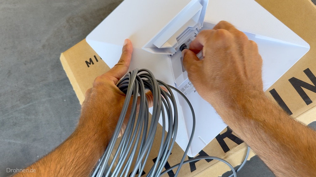 Ein DC-Stecker wird in den Stromanschluss auf der Rückseite des Starlink Mini gesteckt.