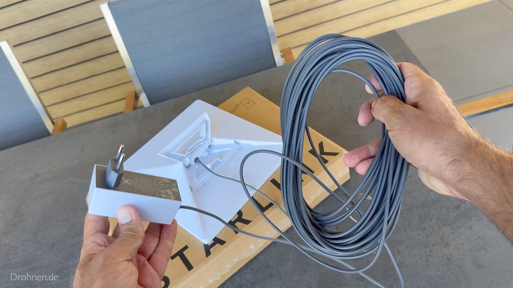Netzteil und aufgerolltes DC-Kabel vor dem rückseitig angeschlossenen Starlink-Mini-Terminal.