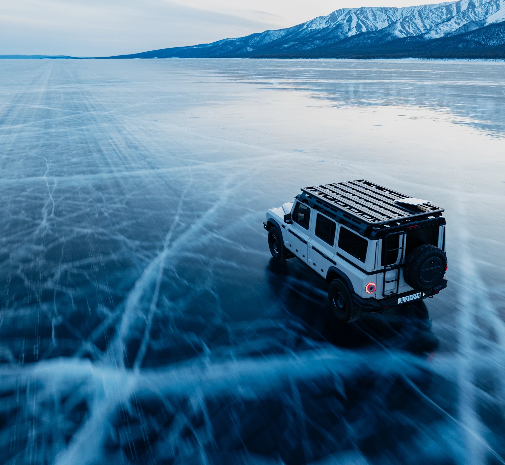 Geländewagen auf einer Eisfläche vor Bergen; Motiv der Starlink-Reiseseite.
