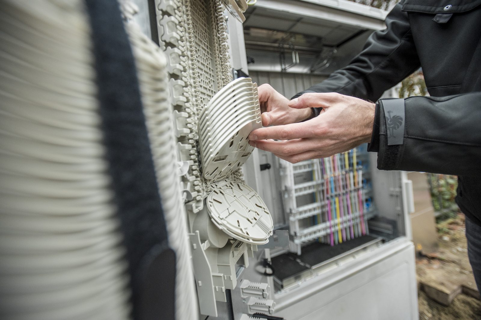 Techniker arbeitet an den Spleißkassetten eines geöffneten Glasfaser-Netzverteilers