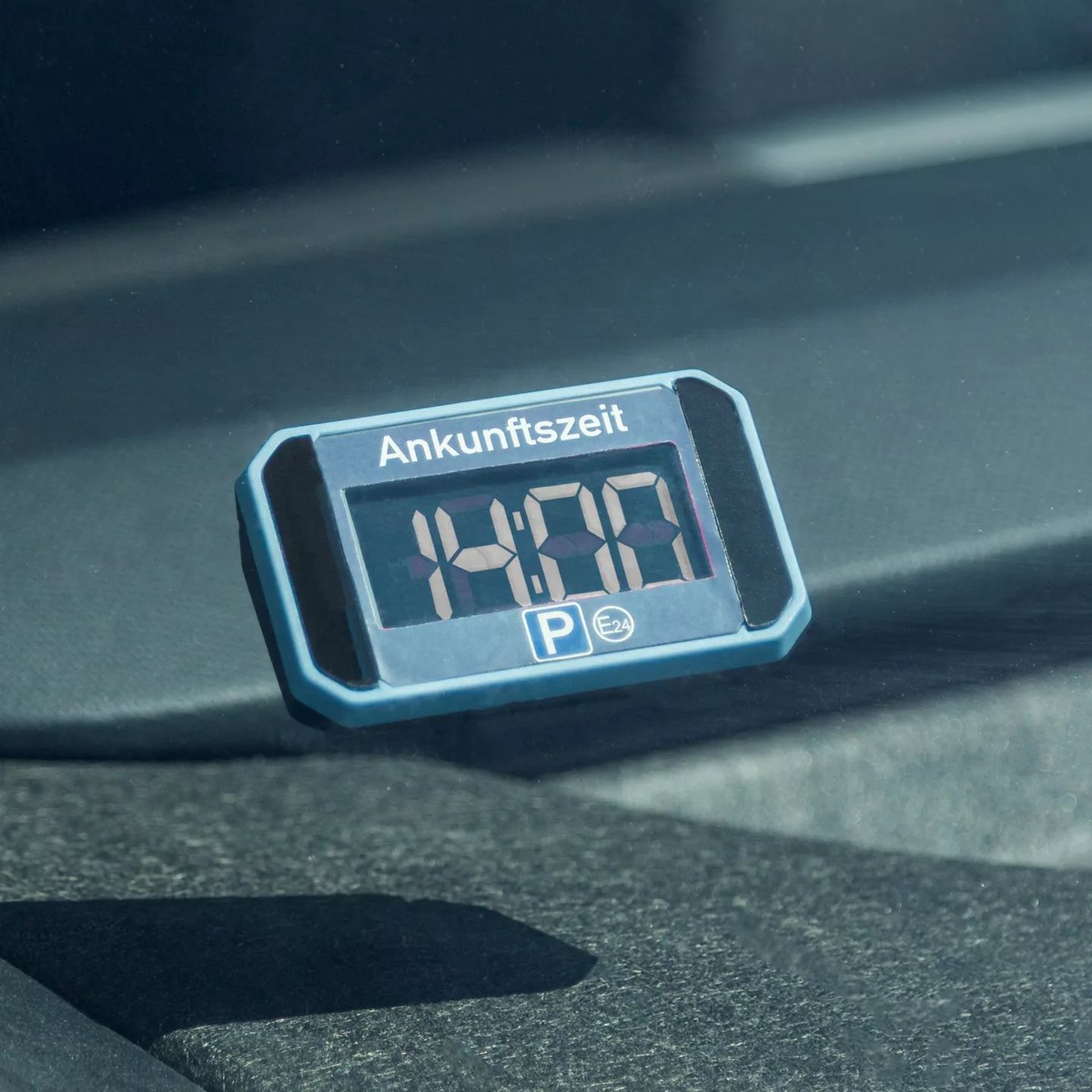 Hellblaue elektronische Parkscheibe RIDE+GO mit der Anzeige 14:00 und dem Wort Ankunftszeit hinter einer Windschutzscheibe