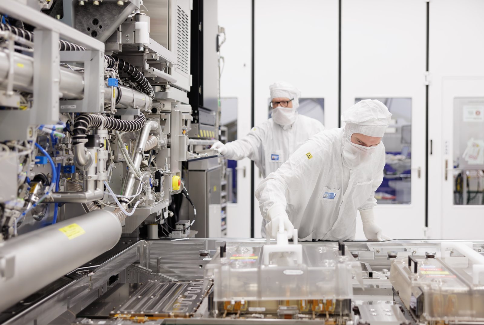 Techniker in Reinraumkleidung arbeiten am Wafer-Tisch eines ASML-Lithografiesystems