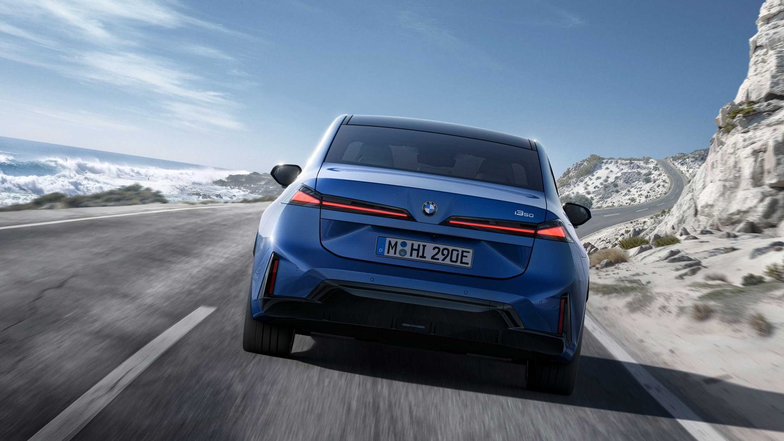 Heckansicht des blauen BMW i3 50 xDrive mit durchgehendem Leuchtenband auf einer Küstenstraße