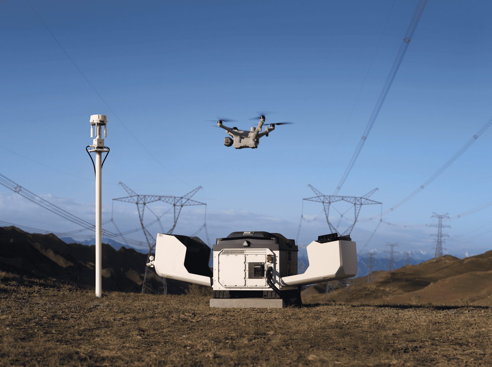 Geöffnete DJI Dock 4 Drohnenstation auf einem Hügel, darüber startet eine DJI Matrice 5TD vor Hochspannungsleitungen