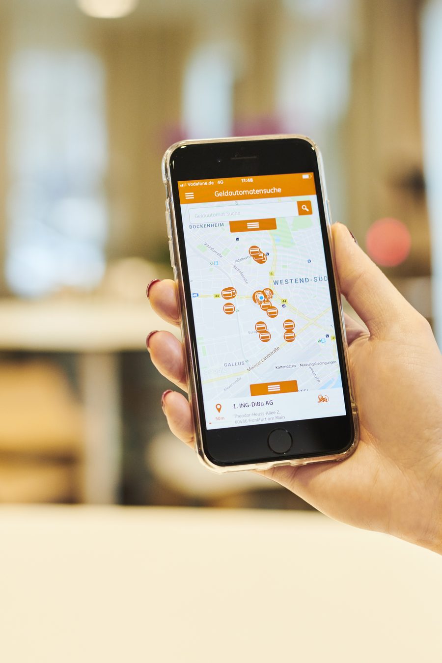 Hand hält ein Smartphone mit der ING-App und einer Geldautomaten-Karte