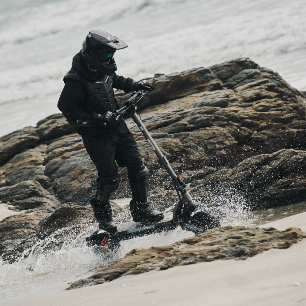 iScooter iX7 Pro – Fahrer auf felsigem Untergrund am Wasser