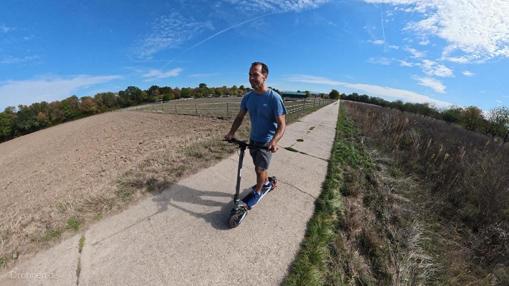 iScooter iX7 Pro auf einem Feldweg aus Betonplatten zwischen Acker und Wiese