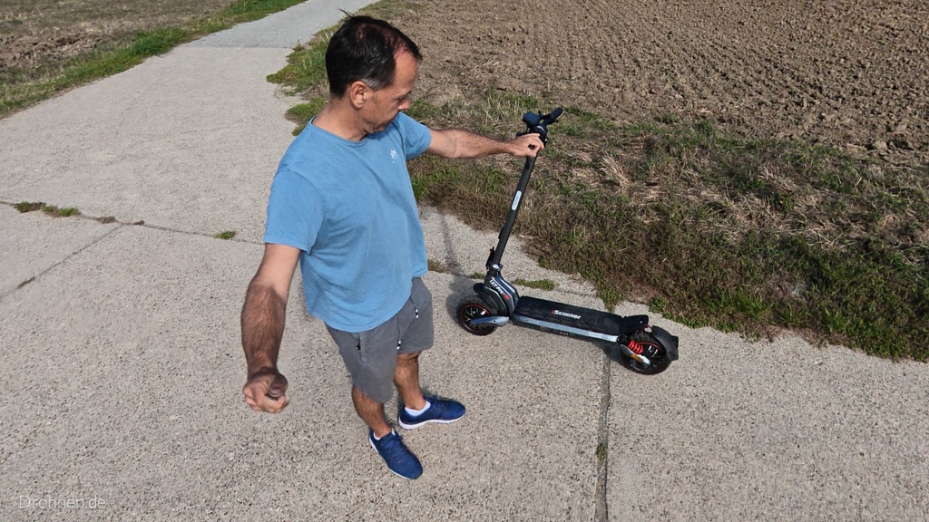 iScooter iX7 Pro von oben, Tester hält den Scooter am Lenker neben einem Acker