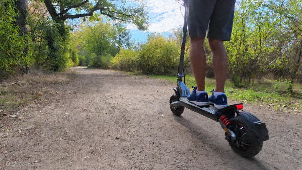 Heck des iScooter iX7 Pro in Fahrt: Rücklicht, rote Feder und breiter Kotflügel