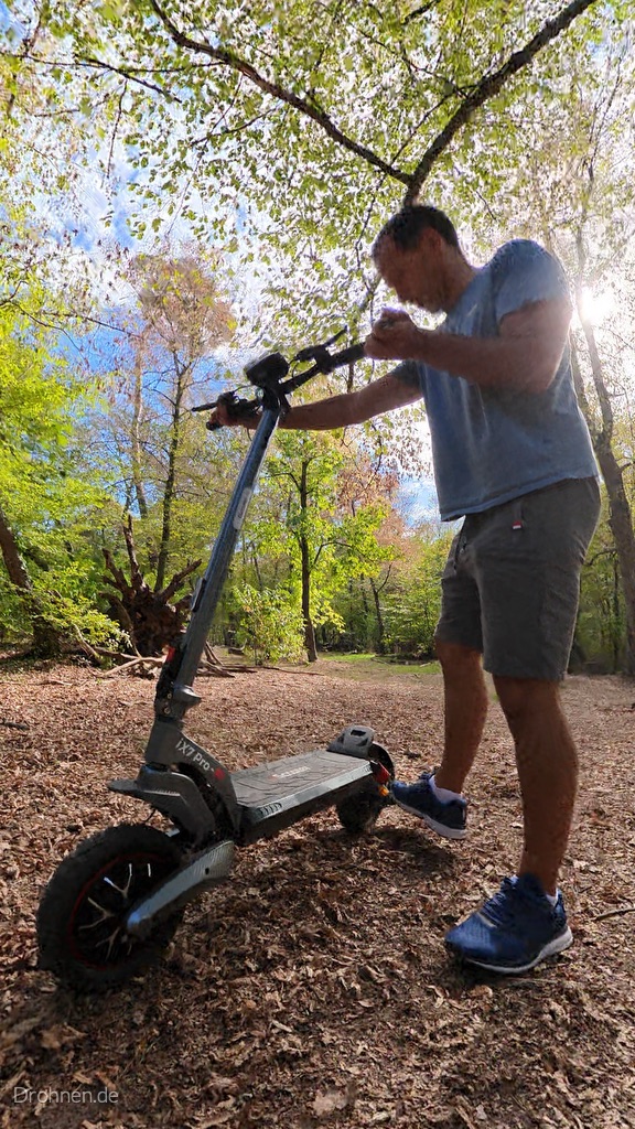 iScooter iX7 Pro aus der Froschperspektive im Wald, Tester greift an den Lenker