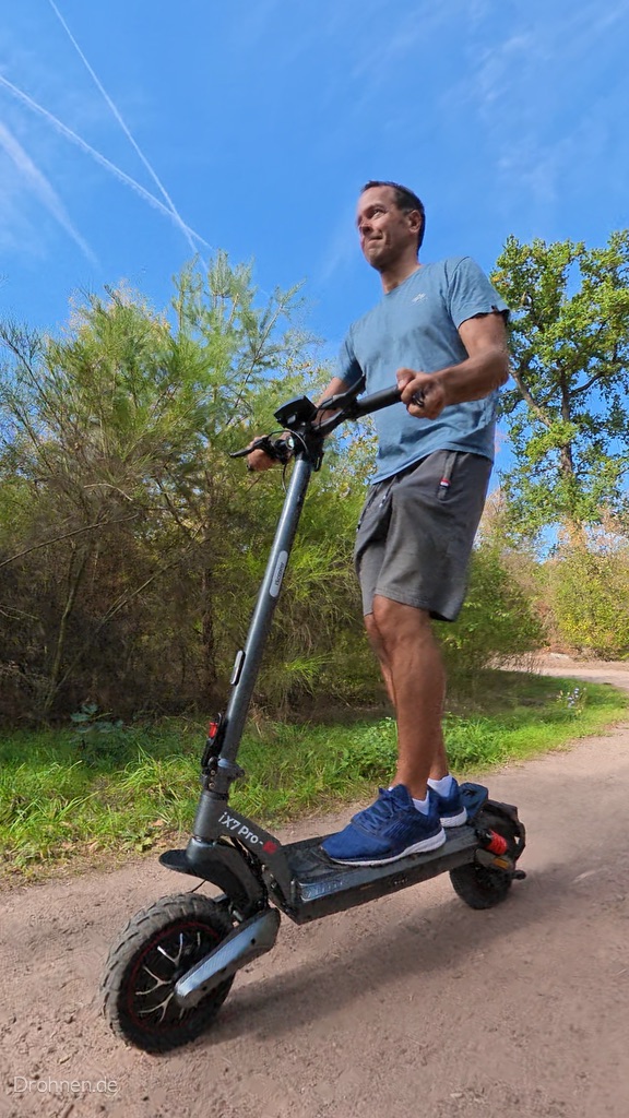 iScooter iX7 Pro von schräg vorn auf einem Sandweg, Vorderrad und Lenksäule im Fokus