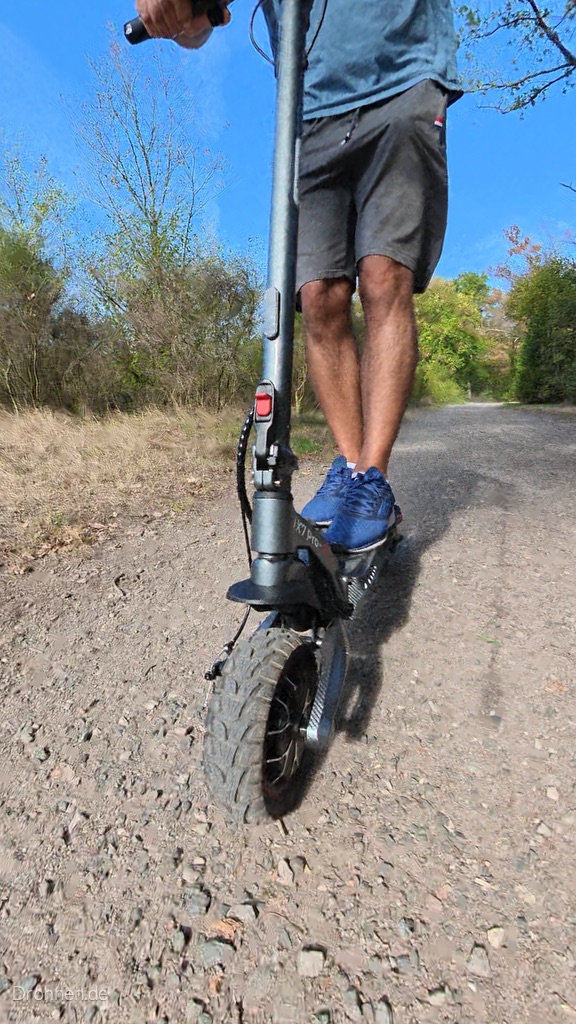 Vorderrad des iScooter iX7 Pro mit breitem Stollenreifen auf grobem Schotter