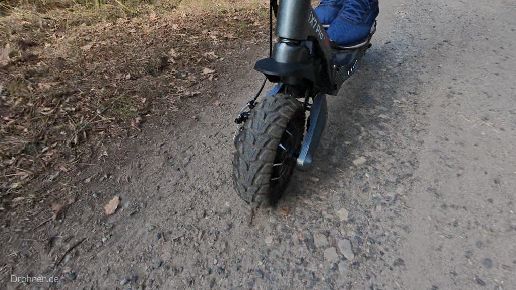 Vorderreifen des iScooter iX7 Pro mit grobem Blockprofil auf steinigem Waldweg