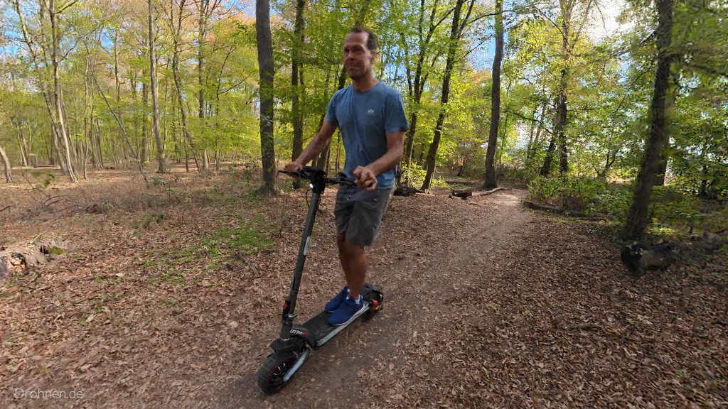 iScooter iX7 Pro auf einem schmalen Waldpfad zwischen hohen Laubbäumen