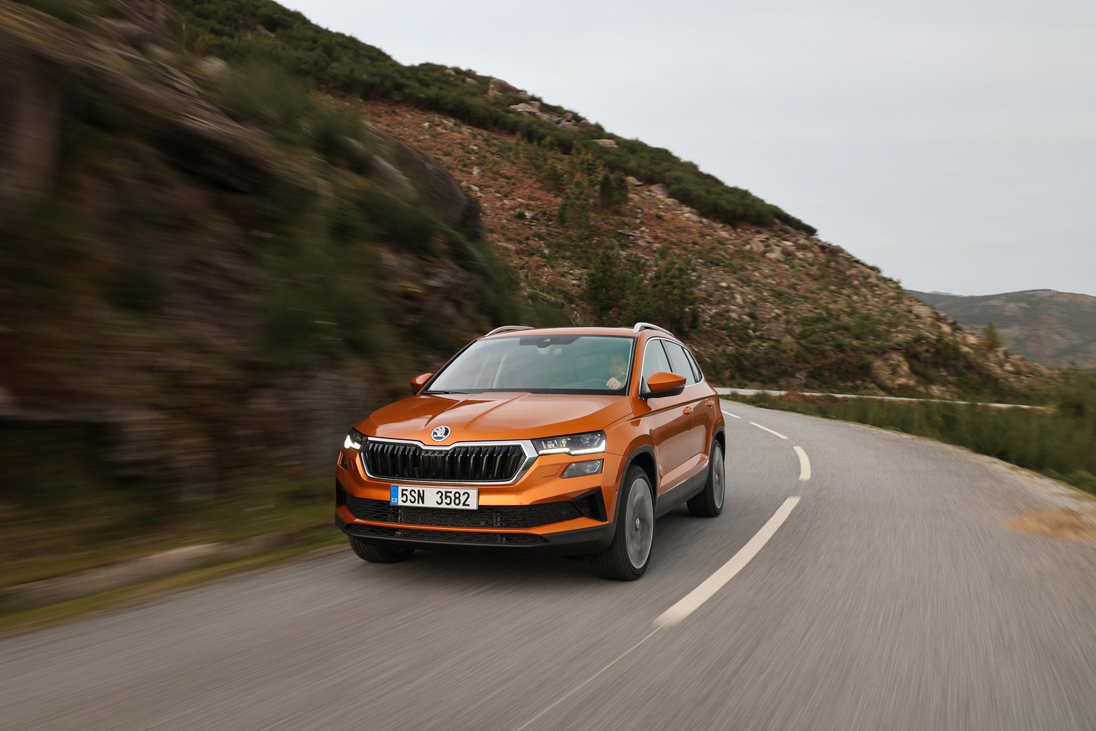 Orangefarbener Škoda Karoq auf einer Küstenstraße