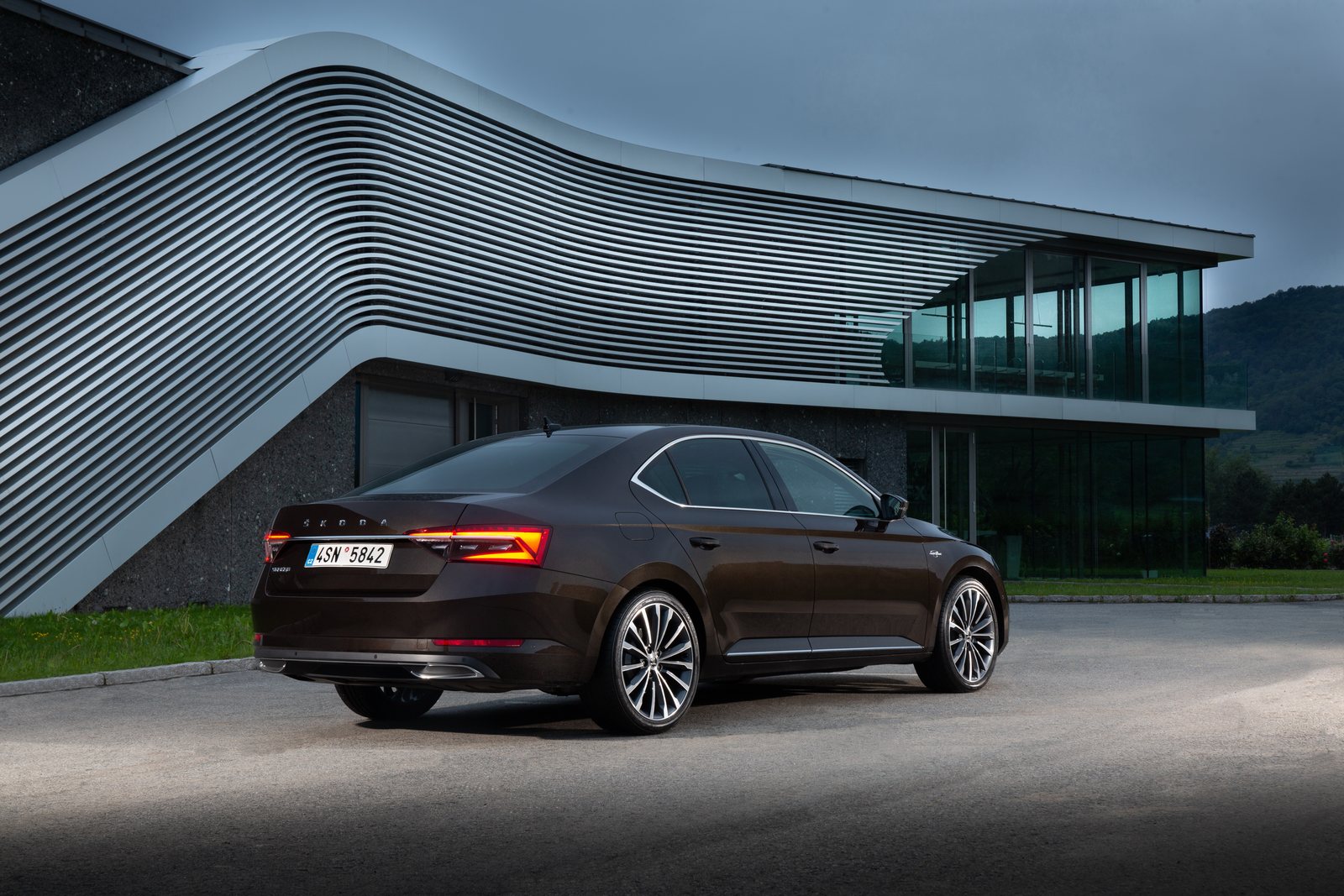 Brauner Škoda Superb L&K in schräger Heckansicht vor einem Gebäude